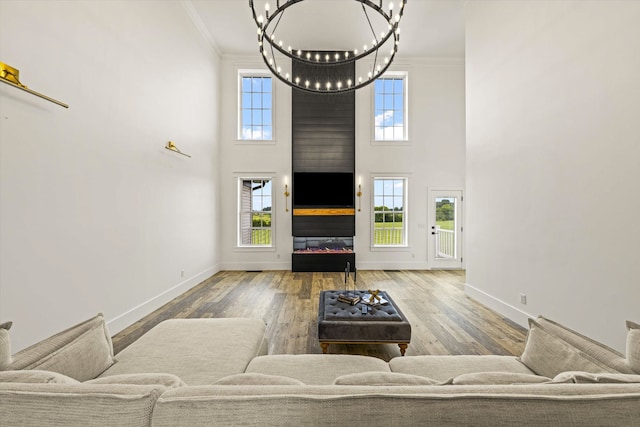 living room featuring an inviting chandelier, crown molding, a high ceiling, and wood-type flooring