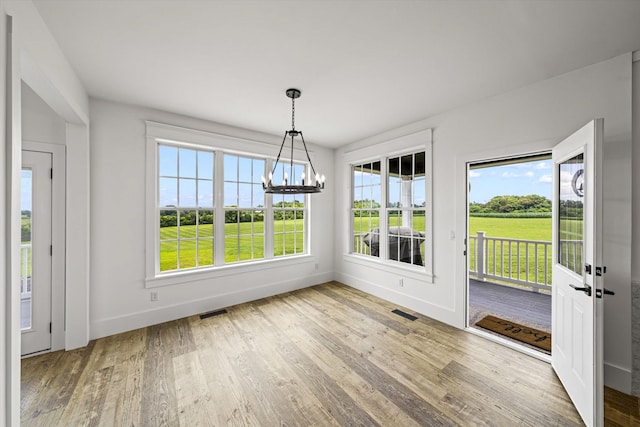 unfurnished dining area with a chandelier and light wood-type flooring