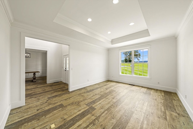 unfurnished room with a raised ceiling, dark hardwood / wood-style flooring, and ornamental molding