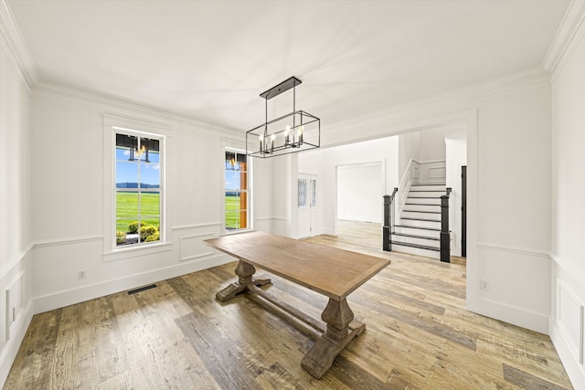 dining room with an inviting chandelier, ornamental molding, and light hardwood / wood-style flooring