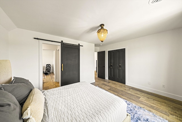 bedroom with a barn door and hardwood / wood-style flooring