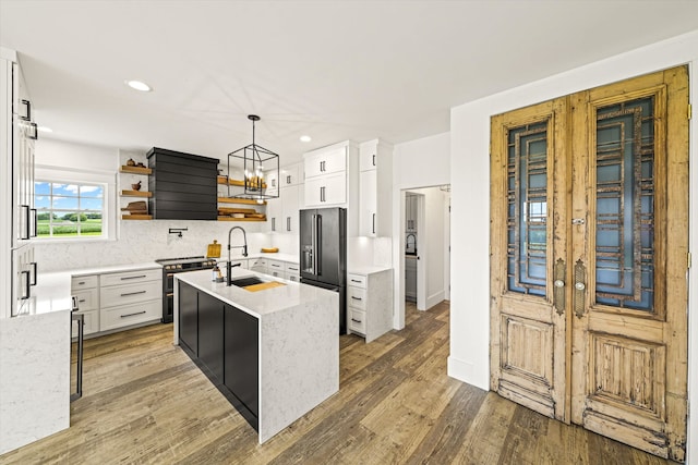 kitchen featuring dark hardwood / wood-style floors, sink, high end fridge, a center island with sink, and tasteful backsplash