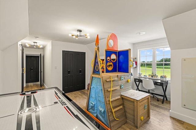 rec room with light hardwood / wood-style flooring and an inviting chandelier