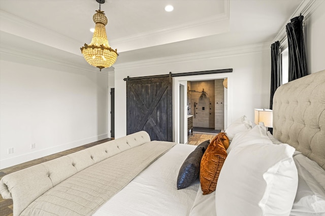 bedroom featuring hardwood / wood-style floors, a barn door, a notable chandelier, ensuite bath, and a raised ceiling