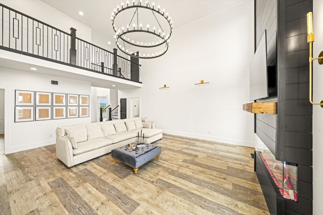 living room with an inviting chandelier, a towering ceiling, and light hardwood / wood-style flooring