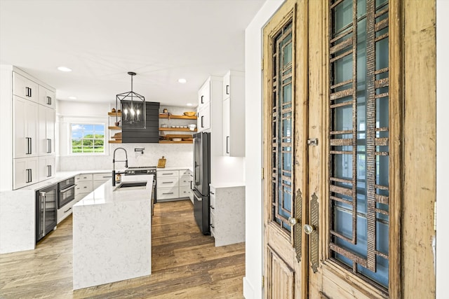 kitchen featuring backsplash, sink, light hardwood / wood-style flooring, white cabinets, and pendant lighting