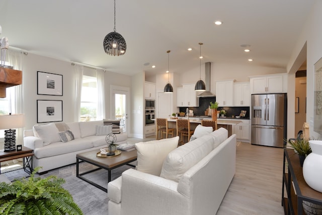 living room featuring lofted ceiling and light hardwood / wood-style floors