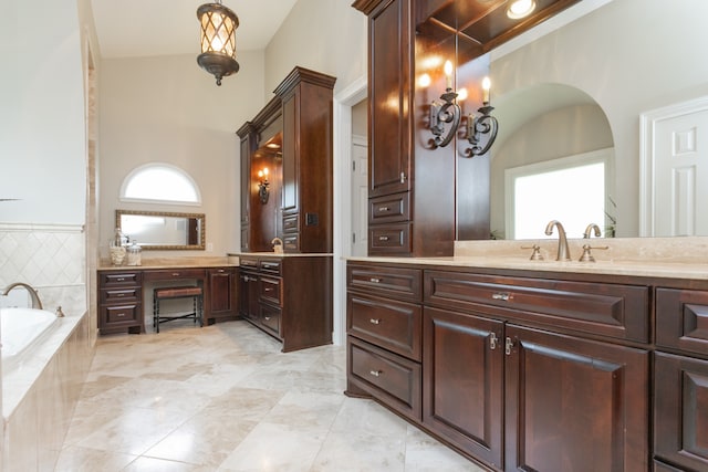 bathroom with tile floors, vanity, and tiled tub