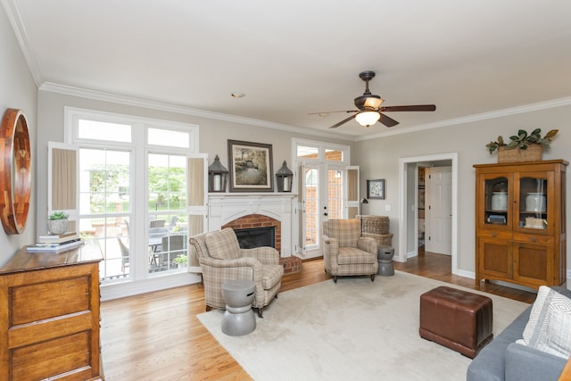 living room with a fireplace, ornamental molding, light hardwood / wood-style floors, and ceiling fan