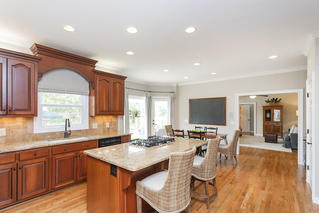 kitchen with light stone counters, a kitchen island, a breakfast bar area, light hardwood / wood-style flooring, and backsplash