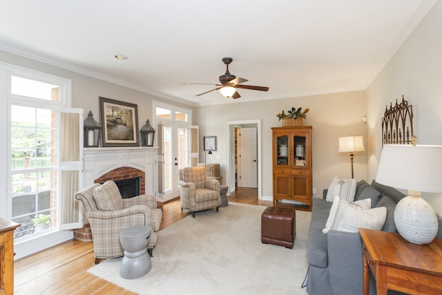 living room featuring plenty of natural light, ornamental molding, a fireplace, and light hardwood / wood-style flooring