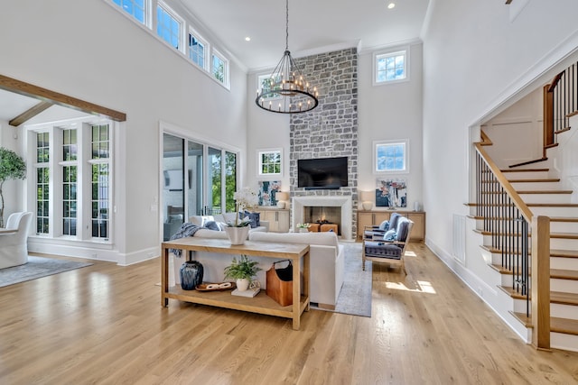 living room featuring a high ceiling, a fireplace, an inviting chandelier, brick wall, and light wood-type flooring