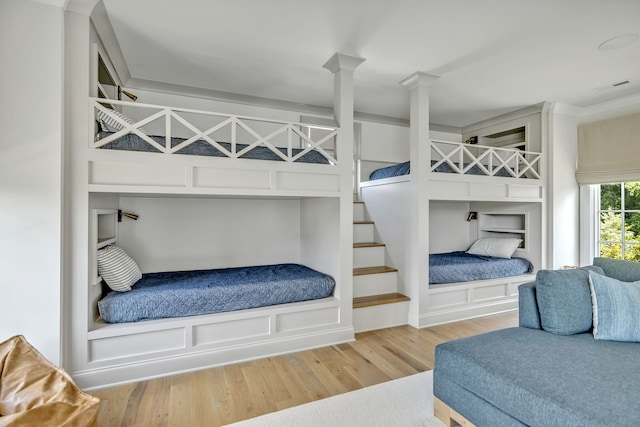 bedroom with light hardwood / wood-style flooring and ornate columns