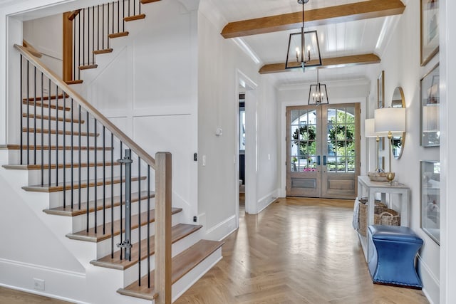 foyer with french doors, crown molding, light parquet floors, beamed ceiling, and a notable chandelier