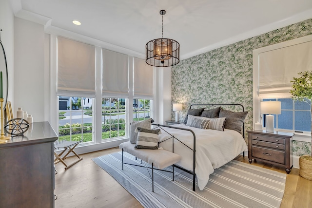 bedroom featuring an inviting chandelier, light hardwood / wood-style floors, and ornamental molding