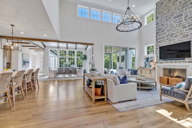 living room featuring a large fireplace, a chandelier, high vaulted ceiling, and light wood-type flooring