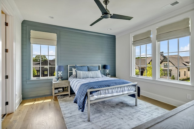 bedroom featuring ceiling fan, light wood-type flooring, and multiple windows