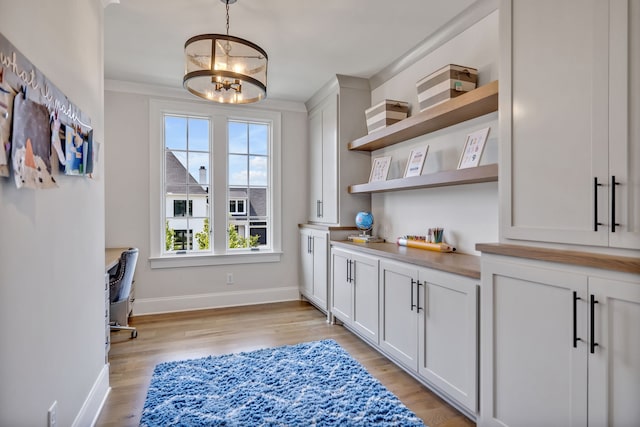 interior space with white cabinets, an inviting chandelier, hanging light fixtures, and light hardwood / wood-style floors