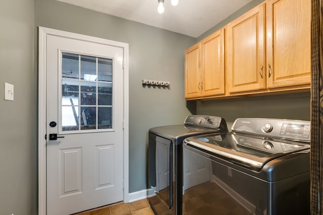 laundry area featuring light tile floors, washer and clothes dryer, and cabinets