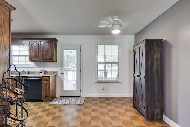 kitchen featuring black dishwasher, dark brown cabinetry, light stone counters, and light tile floors