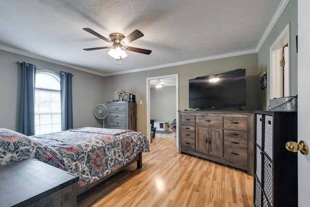 bedroom featuring ceiling fan, light wood-type flooring, ornamental molding, and a textured ceiling