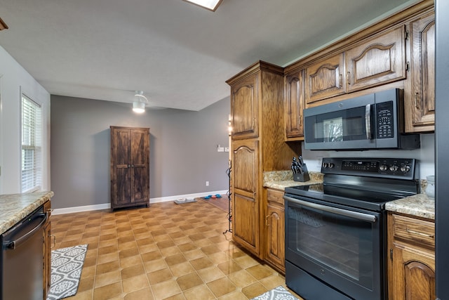 kitchen with appliances with stainless steel finishes, light stone countertops, and light tile floors