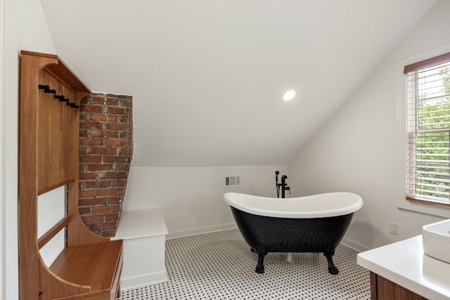 bathroom with lofted ceiling, vanity, and a tub