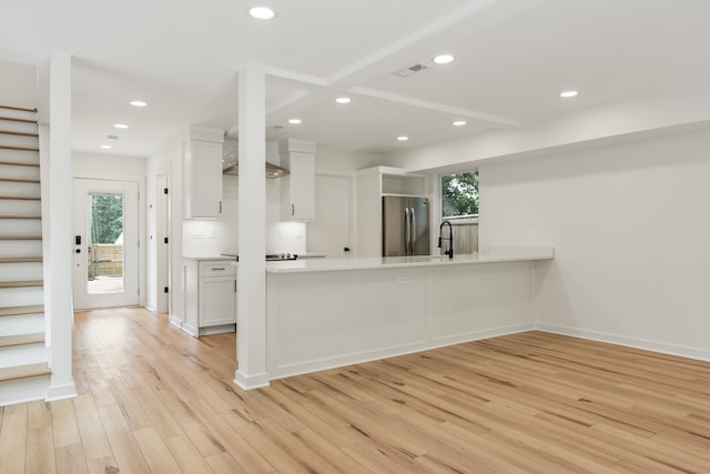 kitchen with light hardwood / wood-style floors, stainless steel refrigerator, and white cabinets