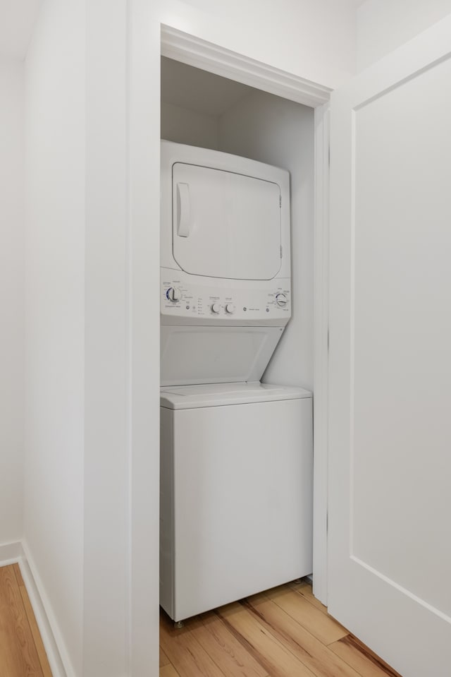 washroom featuring light hardwood / wood-style flooring and stacked washer and clothes dryer