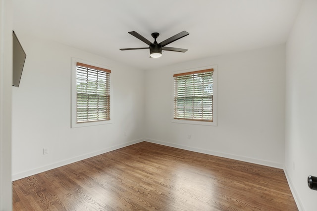 unfurnished room featuring dark hardwood / wood-style flooring, ceiling fan, and a wealth of natural light