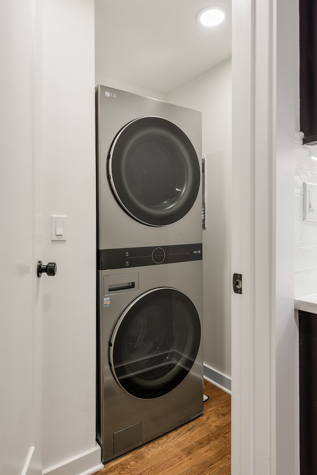 clothes washing area with dark wood-type flooring and stacked washing maching and dryer