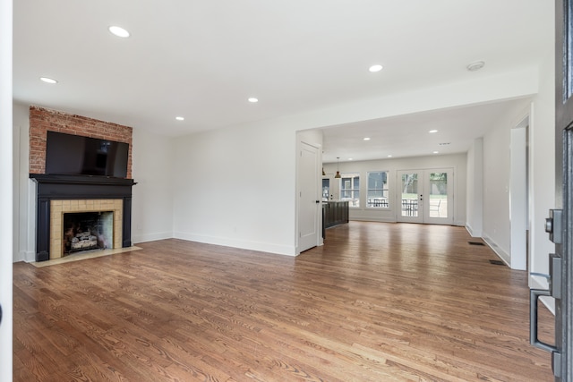 unfurnished living room with french doors, a large fireplace, and hardwood / wood-style floors