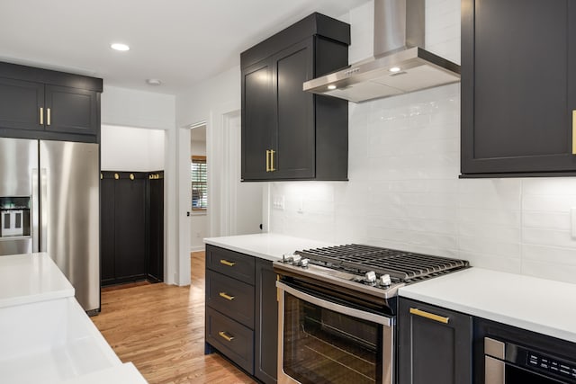 kitchen featuring gas range oven, stainless steel fridge with ice dispenser, light hardwood / wood-style flooring, wall chimney exhaust hood, and tasteful backsplash