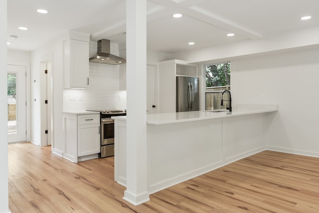 kitchen featuring appliances with stainless steel finishes, backsplash, light hardwood / wood-style flooring, wall chimney exhaust hood, and white cabinets