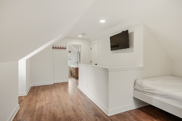 unfurnished bedroom with lofted ceiling, ensuite bathroom, and light hardwood / wood-style flooring