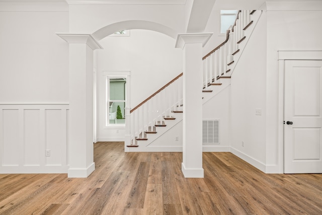 entryway with light hardwood / wood-style flooring and ornate columns