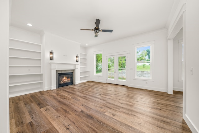 unfurnished living room featuring ceiling fan, built in features, french doors, hardwood / wood-style flooring, and ornamental molding