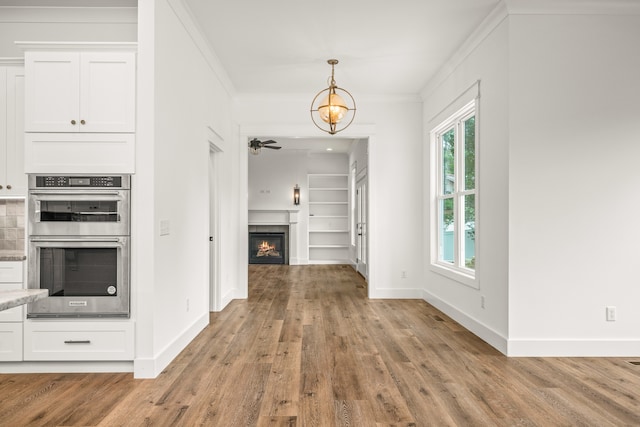 foyer entrance featuring ornamental molding, ceiling fan, and light wood-type flooring