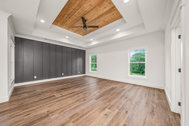 empty room featuring ceiling fan, light hardwood / wood-style floors, a raised ceiling, and wooden ceiling