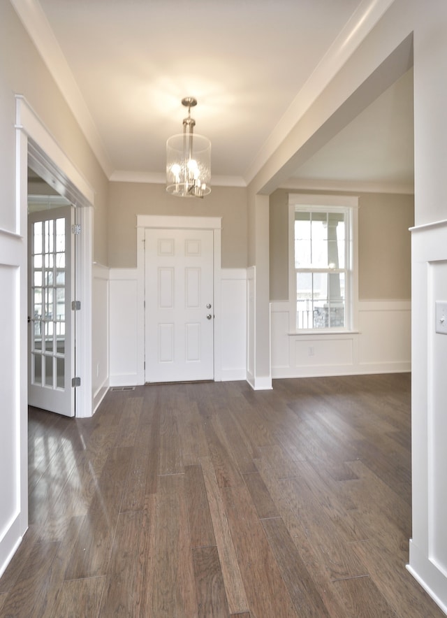 foyer entrance featuring a notable chandelier, dark hardwood / wood-style floors, a healthy amount of sunlight, and ornamental molding