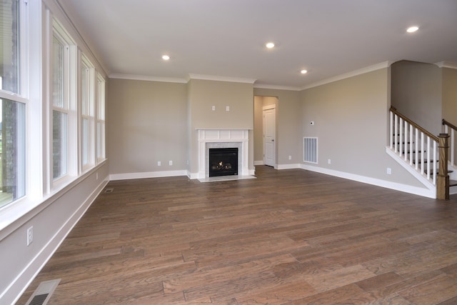 unfurnished living room featuring a high end fireplace, ornamental molding, and dark wood-type flooring