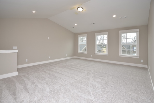 unfurnished room with light carpet, a healthy amount of sunlight, and lofted ceiling