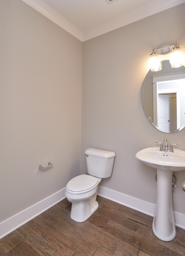 bathroom with hardwood / wood-style floors, toilet, and ornamental molding