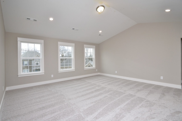 spare room featuring light colored carpet and vaulted ceiling