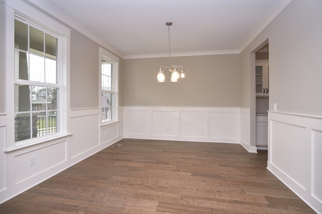 unfurnished dining area featuring a notable chandelier, dark hardwood / wood-style floors, and ornamental molding