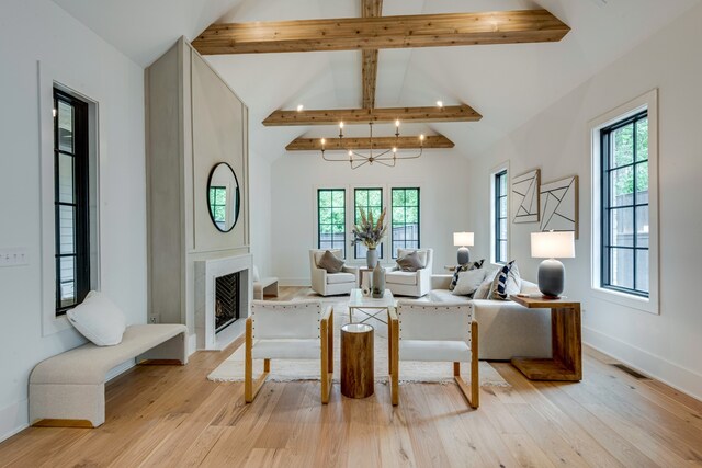 living room with an inviting chandelier, light wood-type flooring, beamed ceiling, and high vaulted ceiling