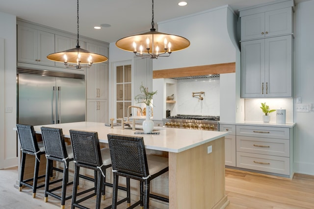 kitchen with a kitchen breakfast bar, stainless steel appliances, tasteful backsplash, hanging light fixtures, and a kitchen island with sink