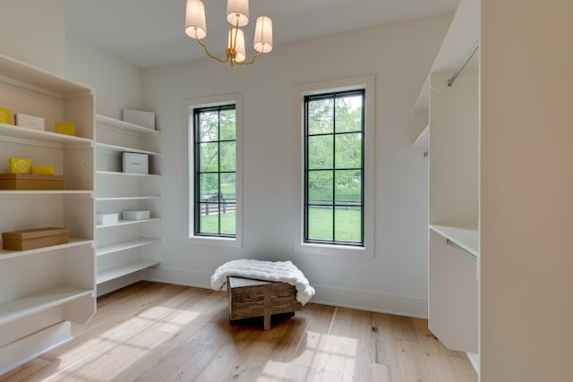 unfurnished room with a wealth of natural light, light hardwood / wood-style flooring, and an inviting chandelier