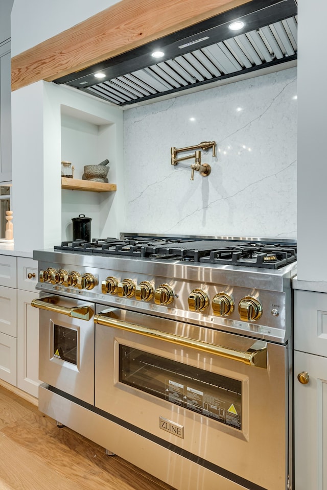 kitchen featuring white cabinets, backsplash, double oven range, and light wood-type flooring