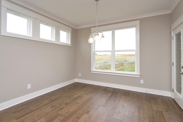 spare room with a notable chandelier, ornamental molding, and dark wood-type flooring